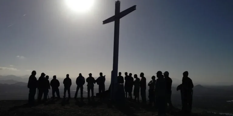 Hermanos de la iglesia orando junto a la cruz en la montaña