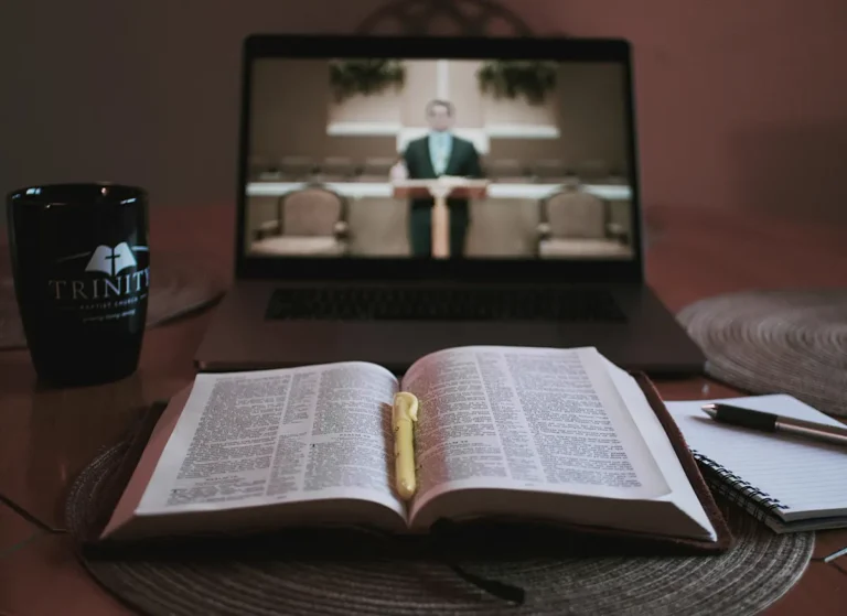 Computadora mostrando un servicio junto a una Biblia
