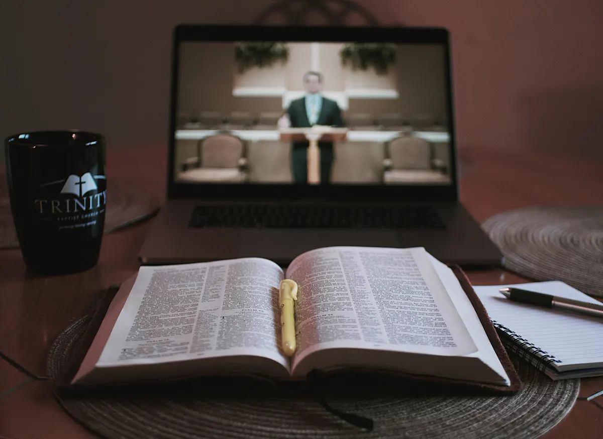 Computadora portátil mostrando un servicio junto a una Biblia abierta